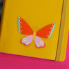 Clear Vinyl Butterfly Sticker. On a yellow notebook. Perfect for journals and water bottles. Nutmeg and Arlo 