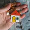 A hand holding a cute house keychain -Nutmeg and Arlo
