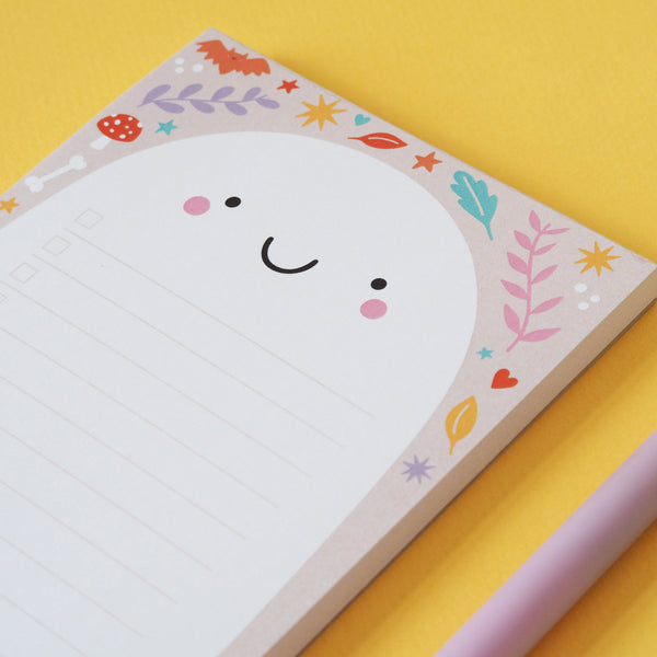 A ghost notepad on a bright yellow background. The notepad has a pretty pattern on the edges - Nutmeg and Arlo