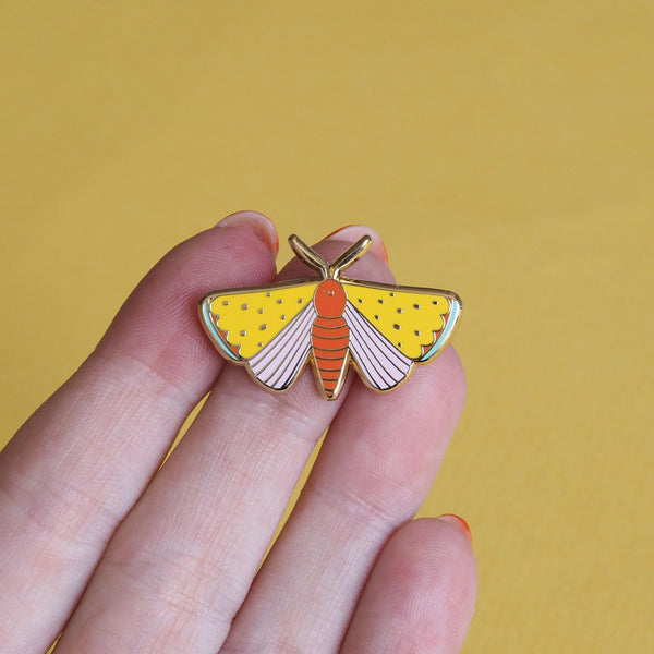 a hand holding a moth enamel pin - nutmeg and arlo