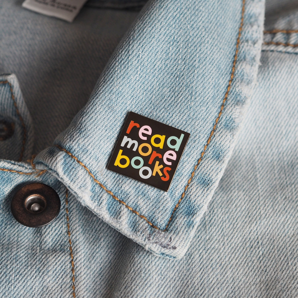 an enamel pin with the words 'read more books' on a denim jacket - nutmeg and arlo