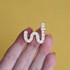a hand holding a worm enamel pin - nutmeg and arlo